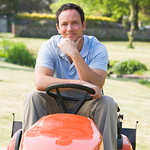 Man outdoors on lawnmower smiling