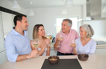 Two couples enjoying wine together in a kitchen